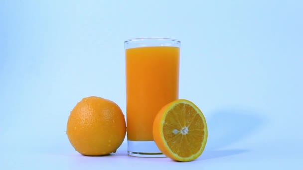 Ett Glas Färsk Apelsinjuice Med Orange Frukter Skivad Hälften Isolerad — Stockvideo