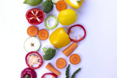 Beyaz arka planda sağlıklı karışık yiyecekler, taze sağlıklı vejetaryen meyve ve sebzeler, brokoli, tatlı çan biberi, havuç, yeşil biber ve limon.