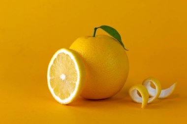 A yellow lemon fruit with leaf and peel slice isolated on yellow background. a creative position of lemon concept design for healthy fruit