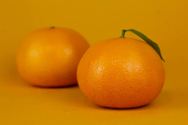 Juicy Orange fruit with leaf isolated on yellow background