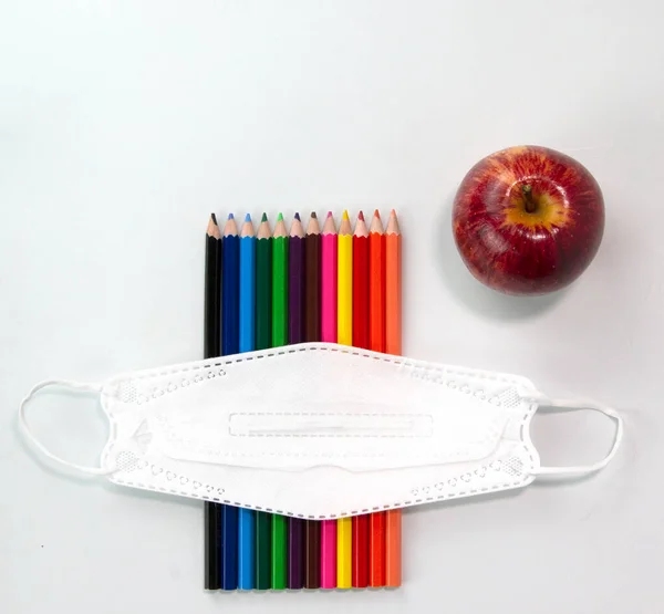 Set of colorful pencils, face mask, apple isolated on white background. Back to school concept on Top view template