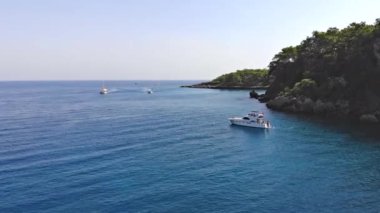 Lüks yatın yanında denizde yüzen insanlar, yukarıdan aşağıya doğru gökyüzü manzaralı.