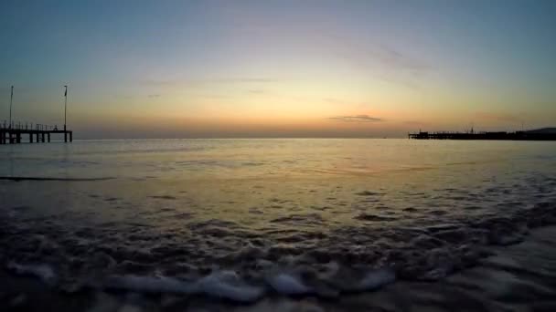 Les vagues mousseuses de la mer roulent sur le sable doré. — Video