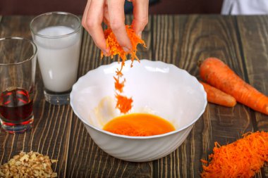 Caucasian womans hand pouring grated carrots into white glass plate