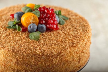 Şeker hastaları için karamel, portakal, nane, nar dilimleri ve yaban mersiniyle süslenmiş ballı kek.