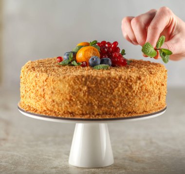 Şeker hastaları için karamel, portakal, nane, nar dilimleri ve yaban mersiniyle süslenmiş ballı kek.