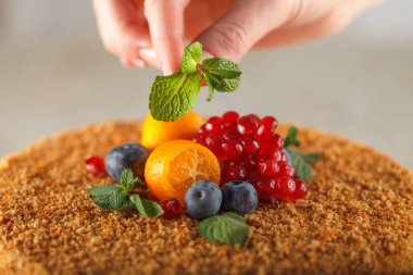 Şeker hastaları için karamel, portakal, nane, nar dilimleri ve yaban mersiniyle süslenmiş ballı kek.