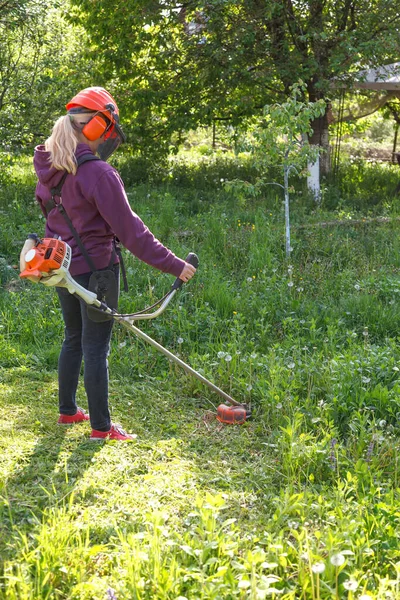 Woman Mows Grass Garden Gasoline Trimmer She Wearing Goggles Helmet — Stok Foto