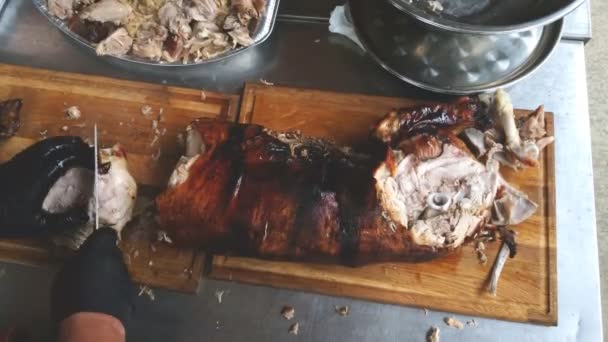 厨师在厨房的切菜台上用一把大刀切烤猪肉 — 图库视频影像