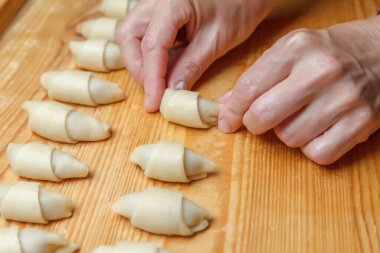 Pasta şefinin elleri hamuru daha fazla kruvasan pişirmek için rulo dolduruyor. Meyveli reçelli Fransız mini kruvasanı. Kapatın. Ev yapımı pişirme konsepti