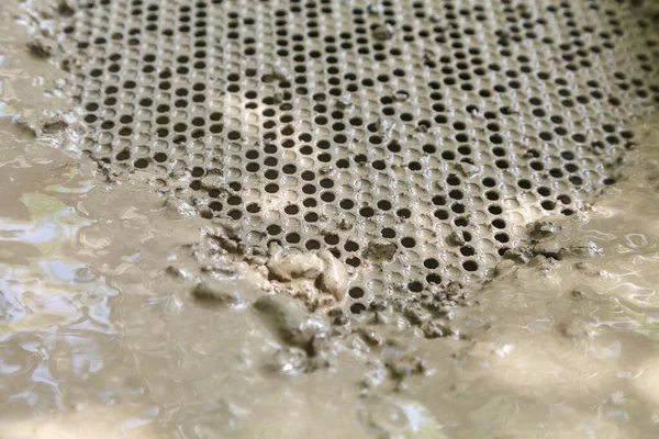 Metal sieve with round holes to clean dirty water from small stones. Cleaning process of stones and clay