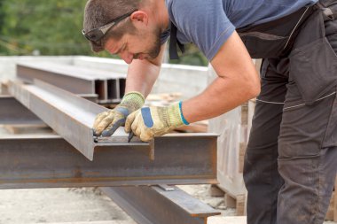 Bir adam daha önce kesme metal ürün işaretler. Açık havada