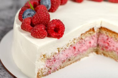 Kremalı lezzetli ahududu keki ve taze ahududu ve nane yapraklarıyla süslenmiş.