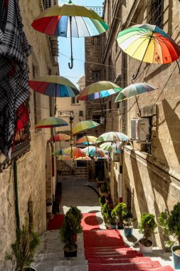 MARDIN, TURKEY - 10 Ekim 2020: Bu şehrin tarihi merkezinde renkli şemsiyelerle süslenmiş eski bir cadde.