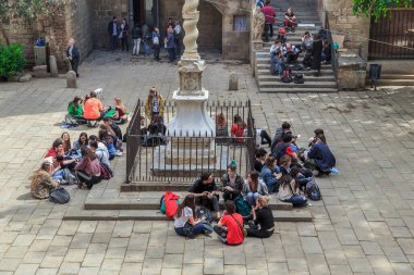 BARCELONA, İspanya - 10 Mayıs 2017: Kimliği belirsiz bir grup genç, şu anda Katalan Edebiyat Kütüphanesi 'ne ev sahipliği yapan bir ortaçağ hastane binasının avlusundaki eski bir sütunun yanında dinleniyor.