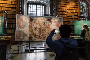 VIENNA, AUSTRIA - MAY 15, 2019: An unidentified woman takes a photo of an old-fashioned copy of a star map on display at the National Library of Austria.