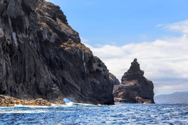 MADEIRA, PORTUGAL - 28 AĞUSTOS 2021 Burası Farol Adası 'nın kayalıkları, arkasında Madeira Adası' nın kıyılarını görebilirsiniz..