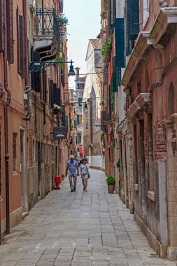 Venedik, İtalya - 18 Mayıs 2018: Kimliği belirsiz çift şehrin turistik olmayan bir bölgesindeki dar bir yaya geçidinde..
