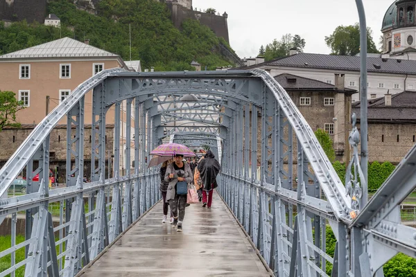 SALZBURG, AUSTRIA - 20 Mayıs 2019: Tanımlanamayan insanlar bahar yağmuru sırasında Art Nouveau Mozartsteg yaya köprüsünde yürüyorlar.