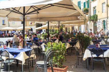 LUCCA, İtalya - 16 Eylül 2019: Roma amfitiyatrosunun uzak geçmişindeki tarihi Piazza Amfiteatrosu 'ndaki pek çok kafeden birinde kimliği belirsiz insanlar dinleniyor.