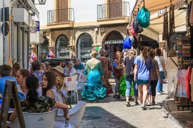 CORDOBA, İspanya - 23 Mayıs 2017: Turist, kafe ve hediyelik eşya dükkanlarıyla dolu eski cadde boyunca ulusal kostümlü kadınlar yürüyor.