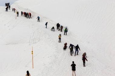 DACHEIN, AUSTRIA - 18 Mayıs 2019: Bir grup tanımlanamayan yürüyüşçü mevsim normalleri dışında kar altında kalmış bir dağ yoluna tırmanıyor.
