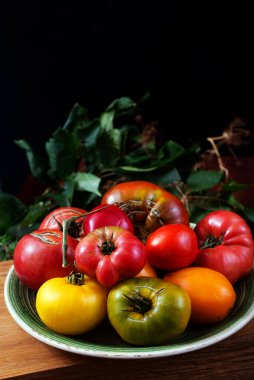 Multicolored homemade organic tomatoes on a dark background. Place for text on top of photo