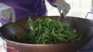 Geleneksel çay yapraklarını kurutma metodu, büyük demir tavada çay yaprakları ve yaprakları eşit şekilde kurutmak için sürekli karıştırma yöntemi.