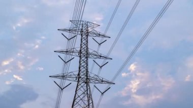 Gün batımında elektrik hattı kulesinin arkasında hareket eden akşam bulutlarının zamanlaması