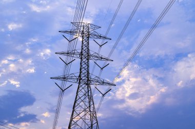 Gün batımında elektrik hattı kulesinin arkasında hareket eden akşam bulutları