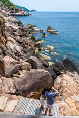 Güneşli bir günde Koh Tao 'nun koyunda deniz manzarası seyreden genç bir çiftin dikey görüntüsü.