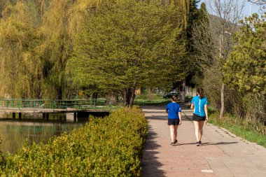 Dilijan, Ermenistan - 27 Nisan 2022 - Ermenistan 'ın Dilijan kentindeki göl kenarında yürüyen iki genç kadın