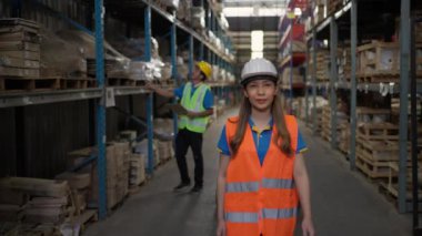 Happy young female warehouse wearing white safety hard hat enjoying working at a warehouse site, smiling at camera