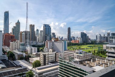 Bangkok, Thailand - 13 August 2022 - Aerial view of Bangkok cityscape in the morning showing high-rises with a golf course and cloudy blue sky