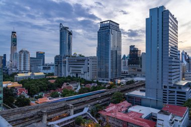 Bangkok, Thailand - 11 August 2022 - Aerial view of Bangkok cityscape in the morning before sunrise showing high-rises and running BTS skytrains and crowded street below