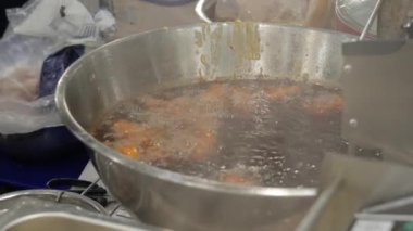 Bangkok, Thailand - 10 August 2022 - Deep fried chicken drums and wings are being cooked in a hot oil pot at a food market in Bangkok, Thailand