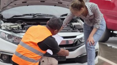 Worried young Asian woman talking to a car insurance agent or technician to claim the repair on her car accident
