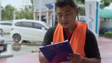 Asian male car insurance agent filling in a car insurance report form