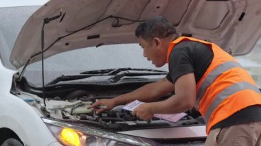 Male auto mechanic checking on the car engine for a car insurance claim