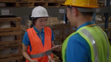 Young female warehouse staff listening and working with her male warehouse supervisor inside of a store warehouse