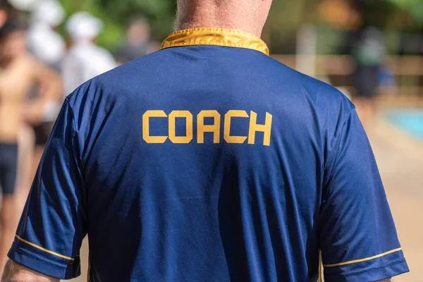 穿着Coach衬衫 在室外游泳池工作的游泳教练的背景图 图库图片