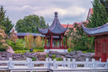Çin bahçesi. Ebedi Mutluluk Bahçesi, insan ve doğa arasındaki uyum. Su, taşlar, binalar, yollar ve rahatlamak için dekoratif unsurlarla eşsiz bir bahçe manzarası. Yaz manzarası
