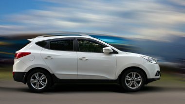 Arka planda bulanık hareket eden beyaz bir araba.