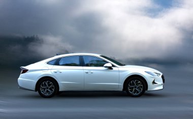 Arka planda bulanık hareket eden beyaz bir araba.