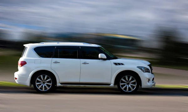 Arka planda bulanık hareket eden beyaz bir araba.