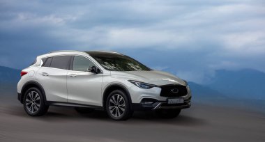 Arkaplanı bulanık olan Infiniti beyaz arabası.