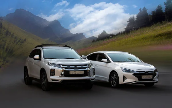 Mitsubishi ve Hyundai beyaz arabaları bulanık doğal arka planda.