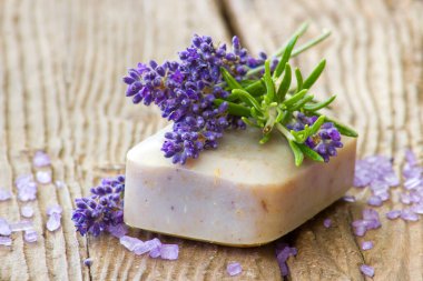 Doğal sabun, lavanta çiçekleri ve ahşap arka planda biberiye.