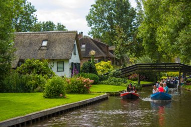 GIETHOORN, NETHERLANDS - 1 Ağustos 2017: Giethoorn 'daki bir kanalda tekne gezisinde bilinmeyen ziyaretçiler. Güzel evler ve bahçıvanlık şehri 
