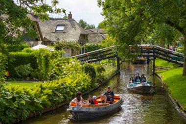 GIETHOORN, NETHERLANDS - 1 Ağustos 2017: Giethoorn 'daki bir kanalda tekne gezisinde bilinmeyen ziyaretçiler. Güzel evler ve bahçıvanlık şehri 